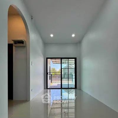 Spacious modern room with glossy floors and large sliding glass doors leading to a balcony.