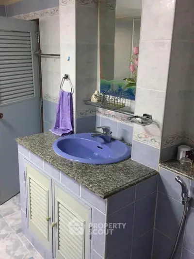 Charming bathroom with blue sink and granite countertop, featuring elegant tile work and modern fixtures.