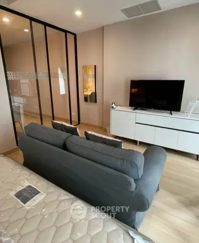 Modern living room with sleek furniture and TV, featuring glass partition and cozy ambiance.