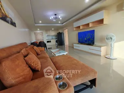 Spacious living room with modern decor and large TV, perfect for relaxation and entertainment.