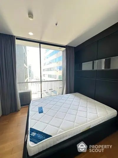 Modern bedroom with large window and city view, featuring a sleek design and natural light.