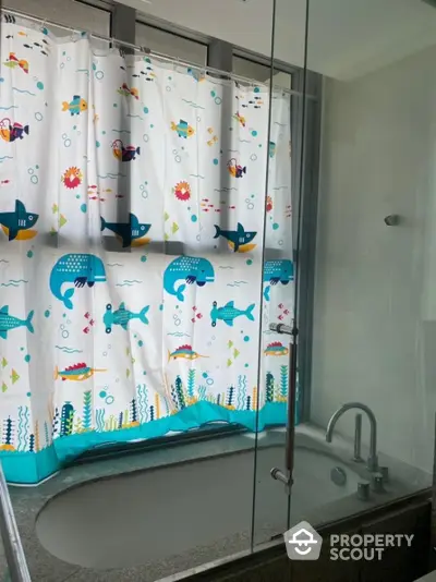 Charming bathroom with playful aquatic-themed shower curtain and modern bathtub.