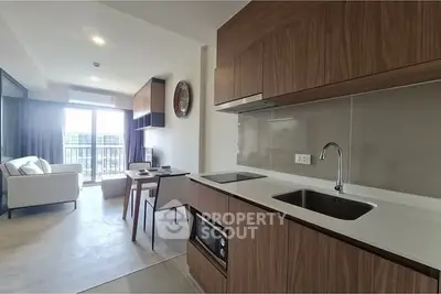 Modern open-layout kitchen with sleek wooden cabinets and cozy dining area in a bright apartment.