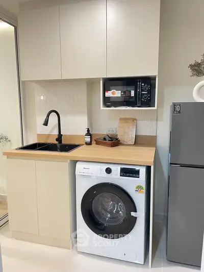 Modern kitchen with washing machine, microwave, and sleek cabinetry