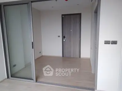 Modern apartment interior with sliding glass doors and wooden flooring.