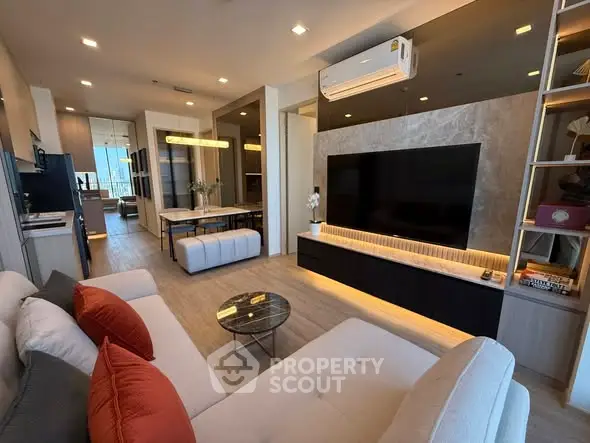 Modern living room with stylish decor, large TV, and open layout leading to dining area.
