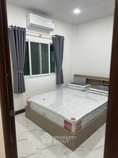 Modern bedroom with air conditioning and stylish curtains, featuring a comfortable bed and sleek design.