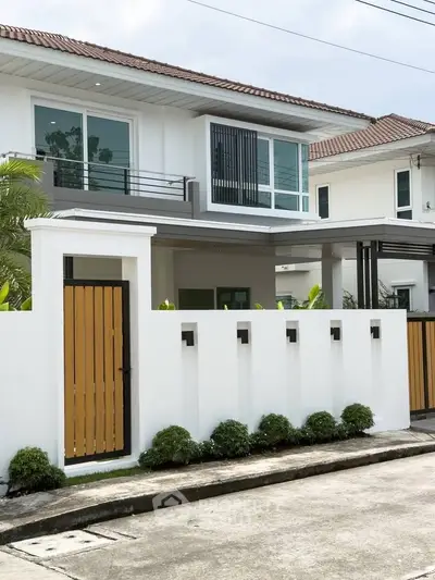 Modern two-story house with white facade and wooden gate in a suburban neighborhood.