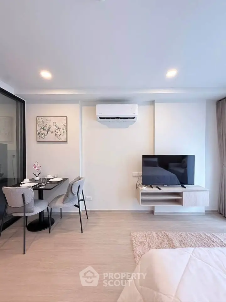 Modern living room with dining area, air conditioning, and mounted TV in a stylish apartment.