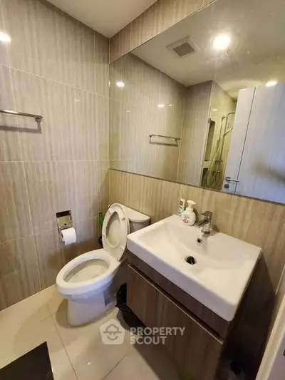 Modern bathroom with sleek fixtures and large mirror in contemporary apartment.