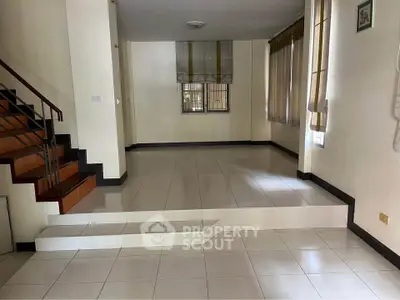 Spacious interior with tiled flooring and staircase, ideal for versatile living arrangements.