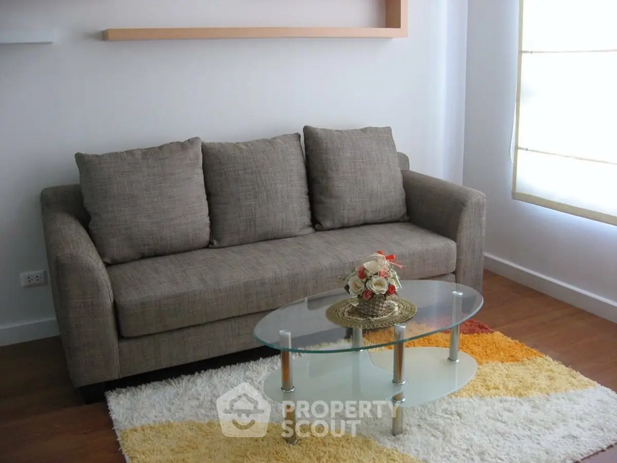Cozy living room with modern sofa and glass coffee table on stylish rug.