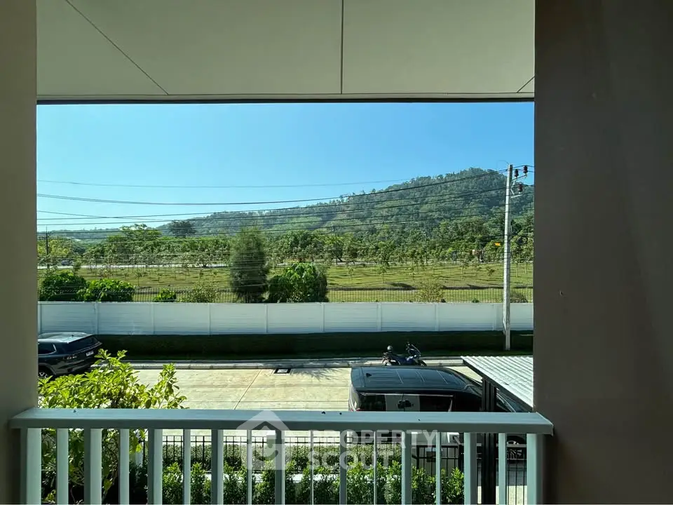 Stunning balcony view overlooking lush greenery and distant hills, perfect for nature lovers.