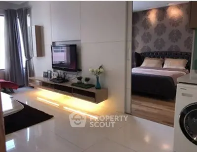 Modern living room with illuminated TV unit and view into stylish bedroom.