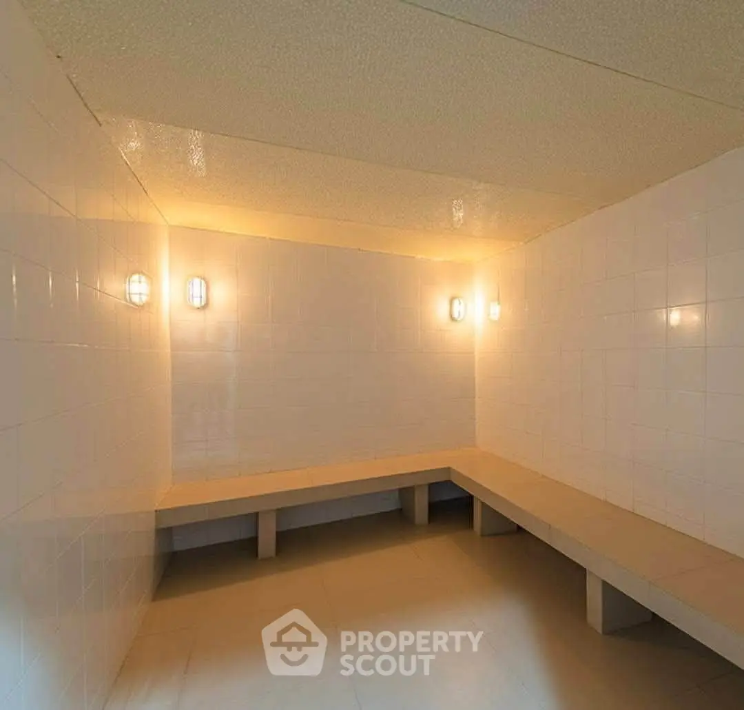 Spacious steam room with tiled walls and ambient lighting in luxury building.