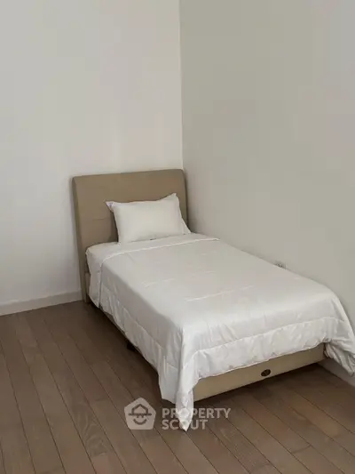 Minimalist bedroom with single bed and wooden flooring, perfect for cozy living.