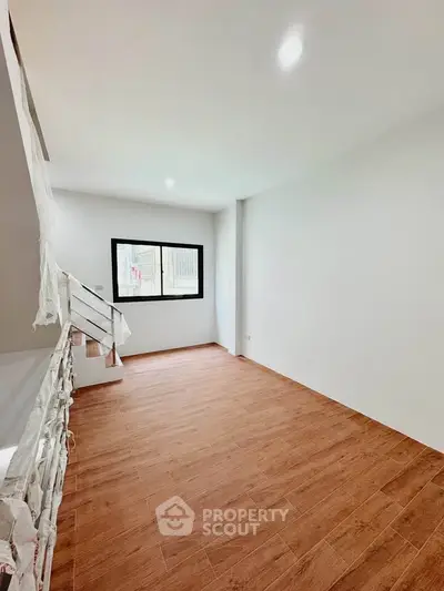 Spacious unfurnished room with wooden flooring and large window