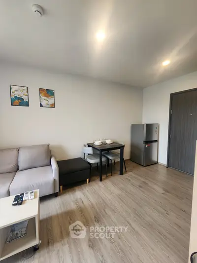 Modern living room with cozy sofa, dining table, and sleek refrigerator in a stylish apartment.