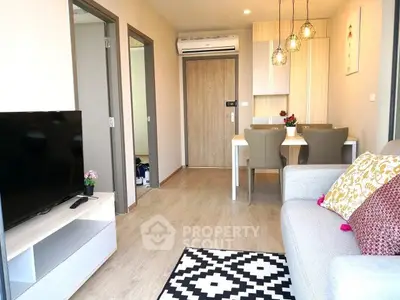 Modern living room with stylish decor and open dining area, featuring cozy seating and contemporary lighting.