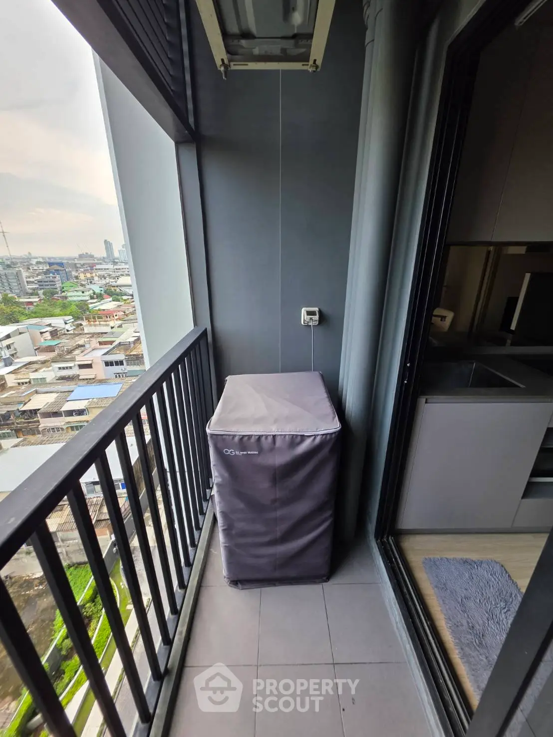 Compact balcony with city view and covered appliance, ideal for urban living.
