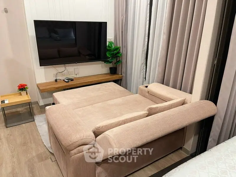 Modern living room with stylish sofa and wall-mounted TV, perfect for relaxation and entertainment.