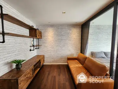 Chic urban living room with white brick walls and rich wooden floors, complemented by a stylish caramel leather sofa.