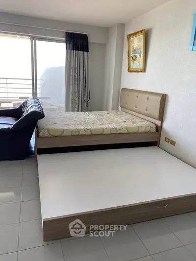 Spacious bedroom with modern furniture and large window offering natural light and balcony access.