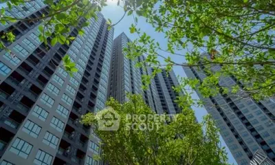 Stunning high-rise apartment building with lush greenery and clear blue sky.