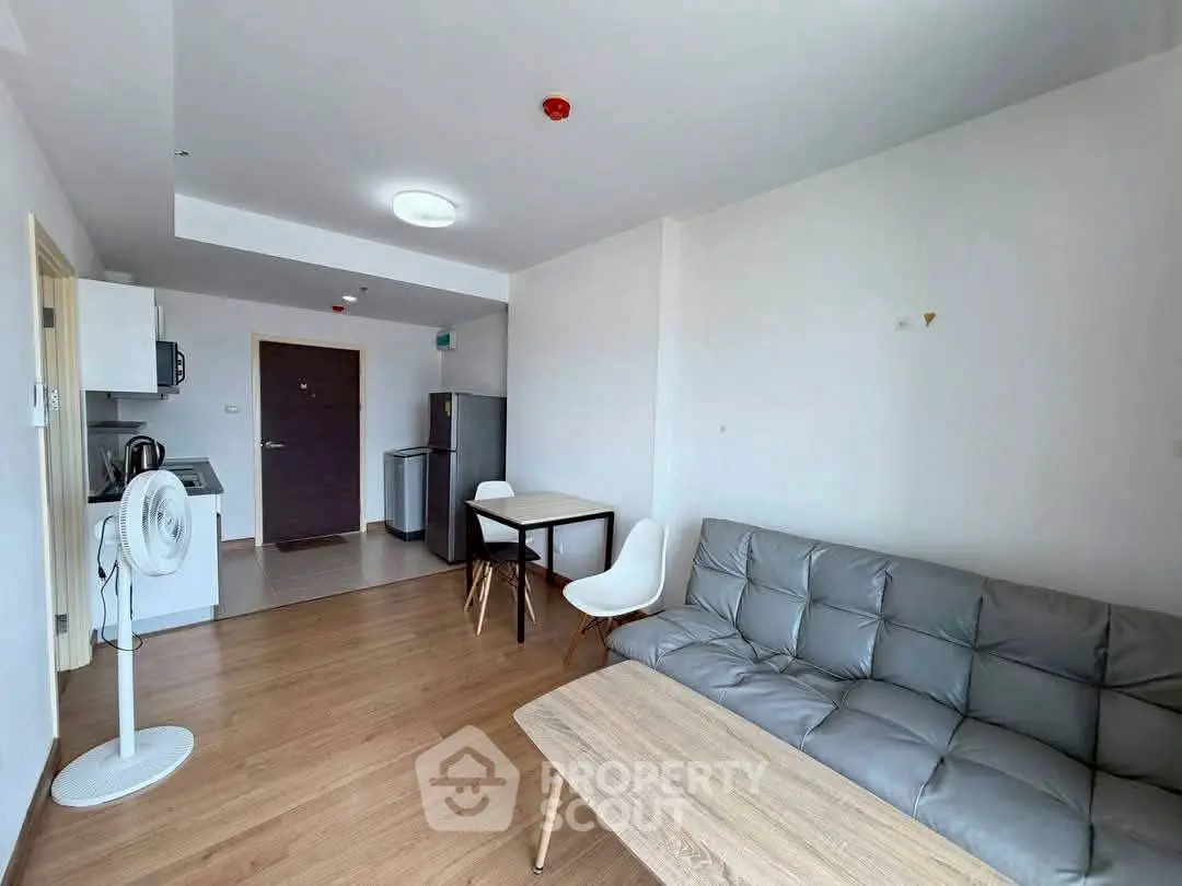 Modern living room with open kitchen, stylish sofa, and dining area in a bright apartment.