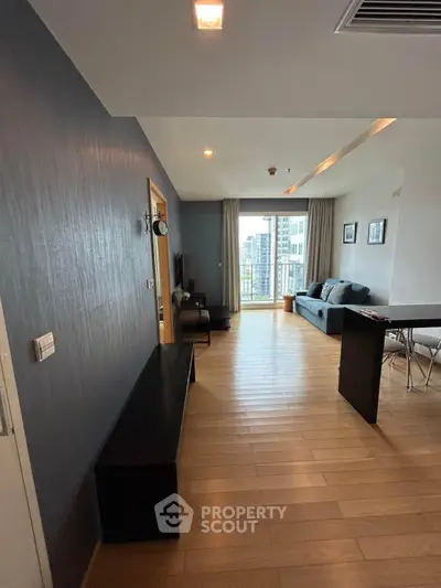 Spacious modern living room with wooden flooring and city view balcony.