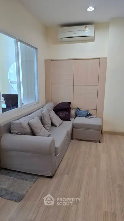 Cozy living room with modern sofa and air conditioning, perfect for relaxation.