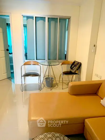 Cozy living room with modern furniture and glass table, perfect for relaxation.