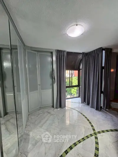 Elegant bedroom with marble flooring and large windows offering natural light.