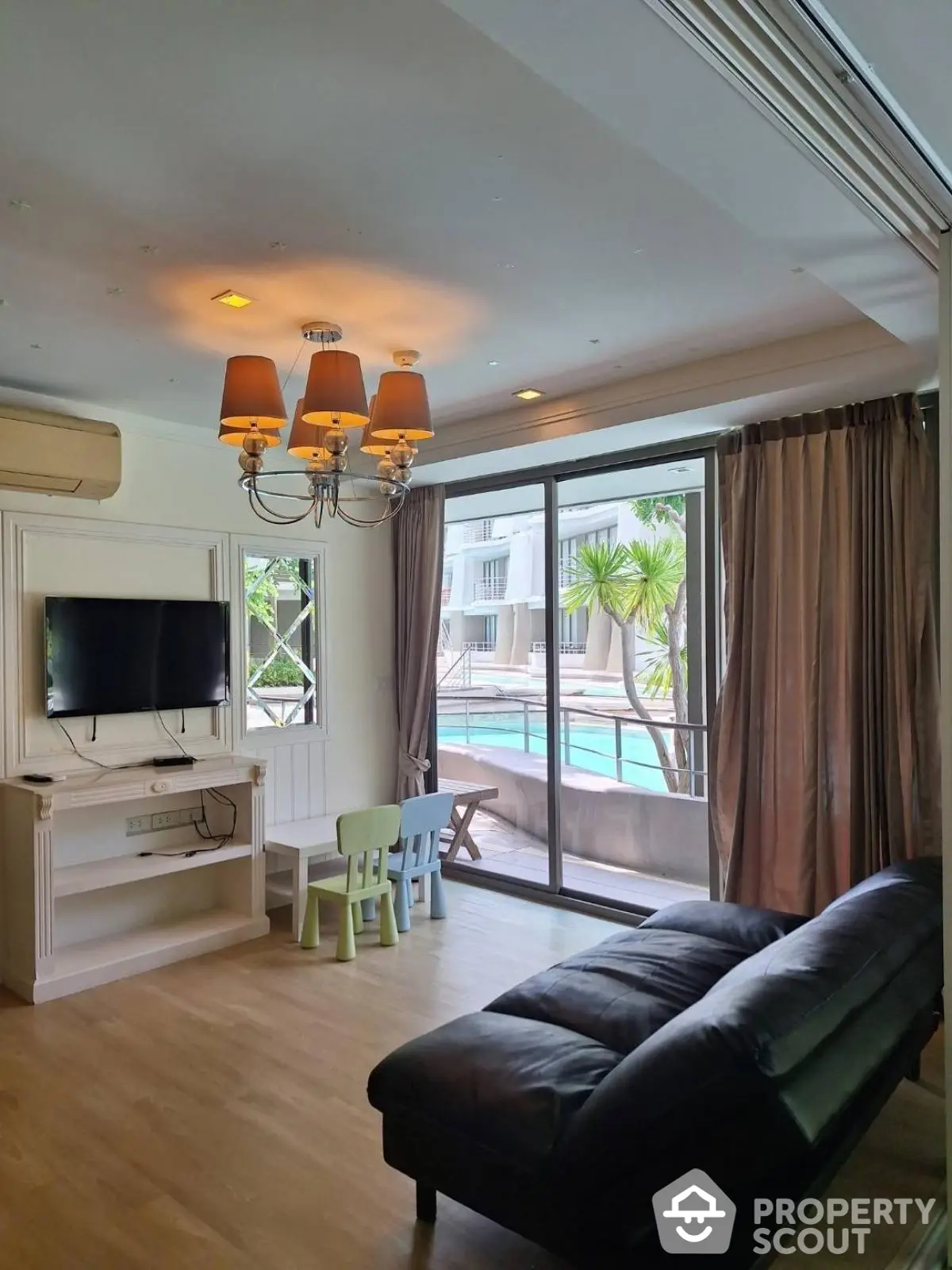 Spacious living room with pool view, elegant chandelier, and modern furnishings in luxury apartment.