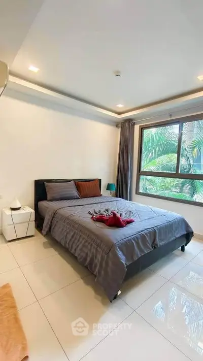 Spacious bedroom with large window and modern decor in a serene setting.