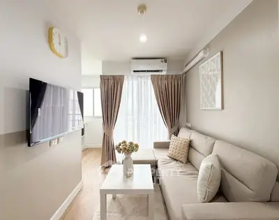 Modern living room with cozy sofa, wall-mounted TV, and natural light from large window.