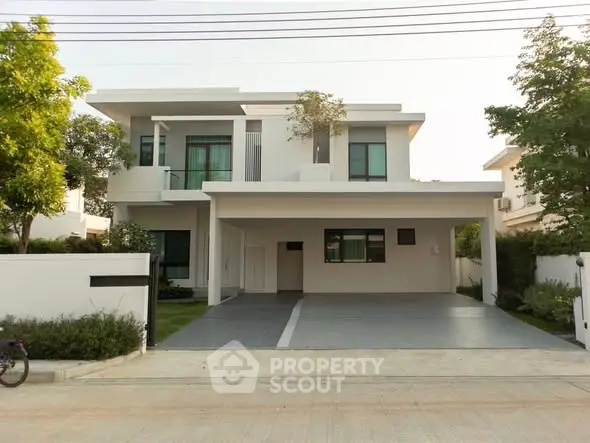 Modern two-story house with spacious driveway and lush greenery