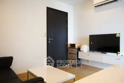 Modern living room with sleek furniture and flat-screen TV, featuring minimalist design and air conditioning.