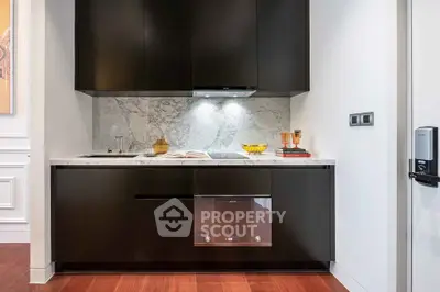 Modern kitchen with sleek black cabinets and marble backsplash, featuring built-in oven and elegant lighting.