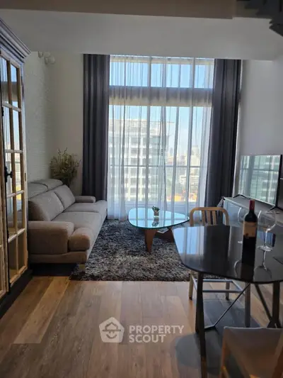 Modern living room with floor-to-ceiling windows and city view, featuring stylish furniture and elegant decor.