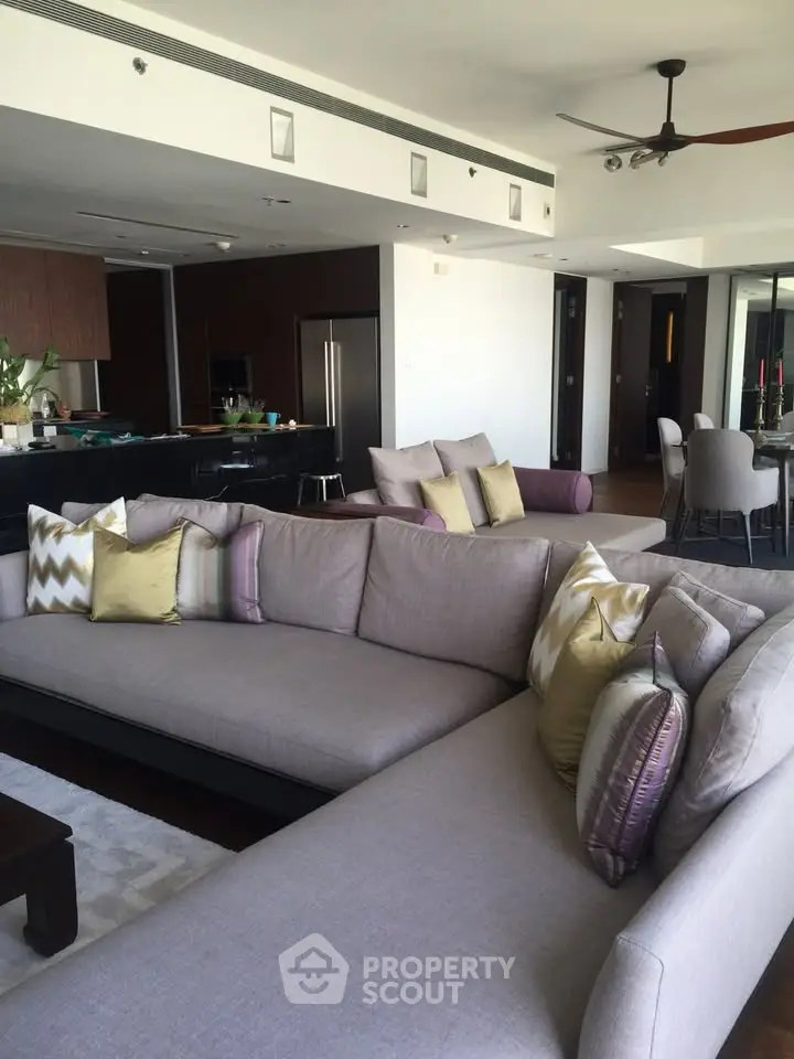 Spacious modern living room with elegant sectional sofa and open kitchen layout in luxury apartment.