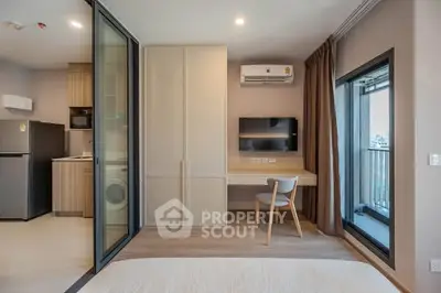 Modern studio apartment with balcony, featuring a compact kitchen and stylish interior design.