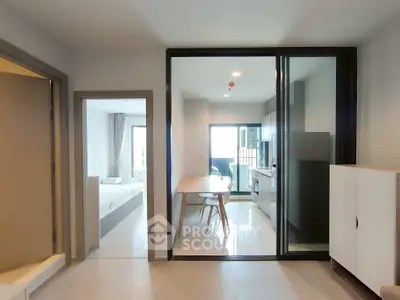 Modern open-plan apartment with kitchen and dining area leading to a bright bedroom.