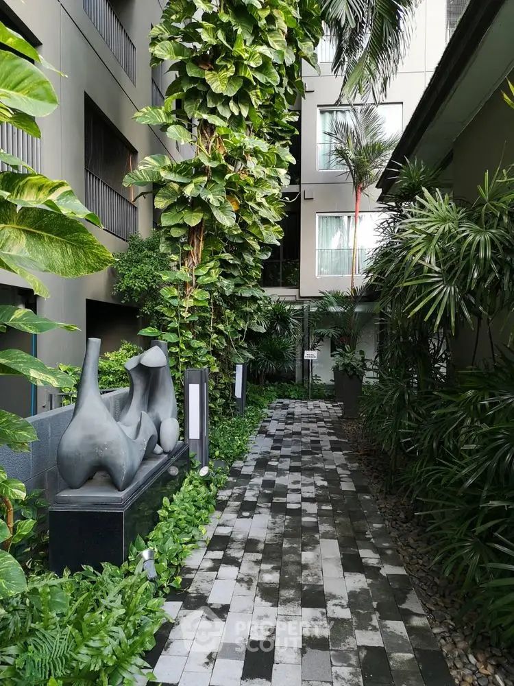 Modern apartment building with lush garden and artistic sculptures