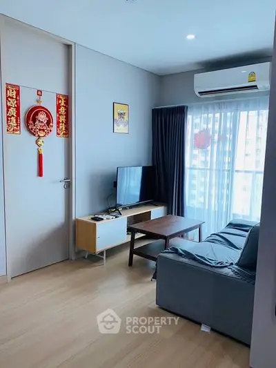 Modern living room with cozy sofa, TV, and large window for natural light.
