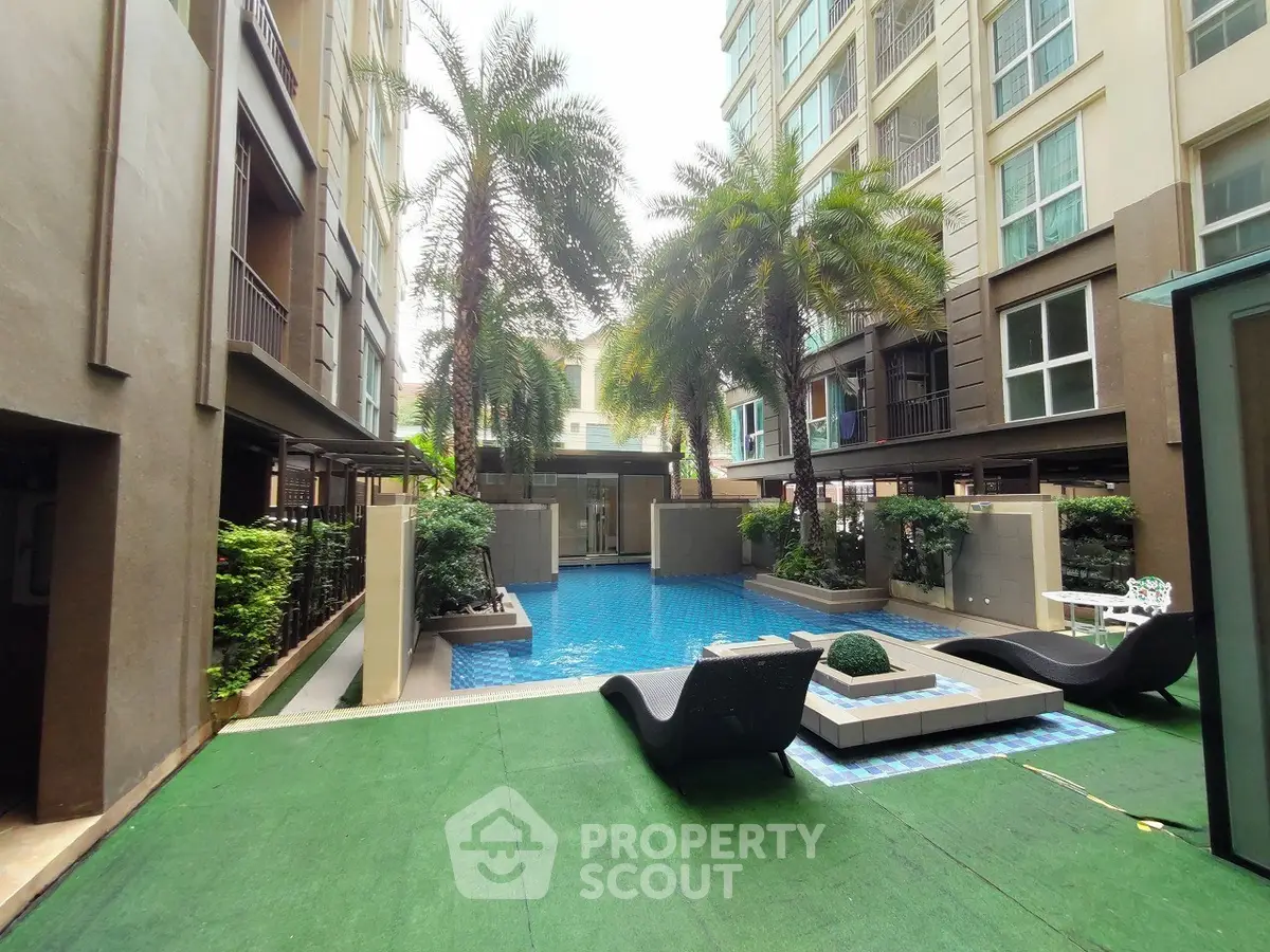 Luxurious condominium pool area with lush greenery and modern lounge chairs