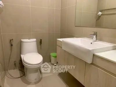 Modern bathroom with sleek fixtures and neutral tones, featuring a spacious sink and contemporary toilet design.