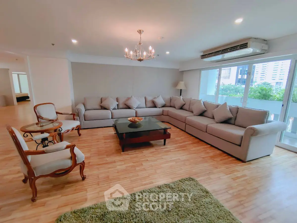 Spacious living room with elegant chandelier and large sectional sofa in modern apartment.