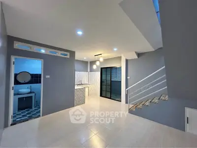 Modern open-plan living area with sleek staircase and stylish kitchen in contemporary home.