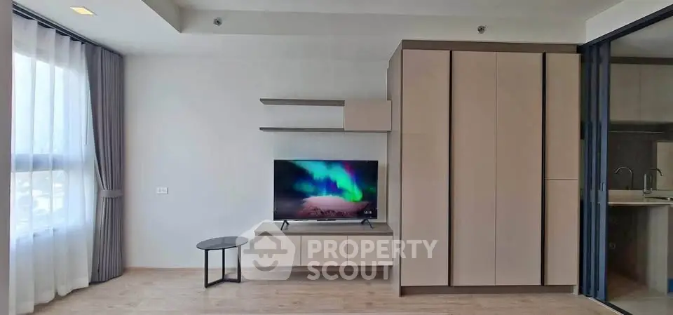 Modern living room with sleek TV setup and large wardrobe, featuring natural light and minimalist design.